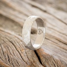 a wedding ring sitting on top of a piece of wooden planked surface with the word love written in it