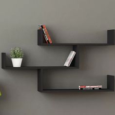 two wooden shelves with books on them against a gray wall next to a green lamp