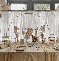 the table is set up for a baby shower with clothes hanging from it's line