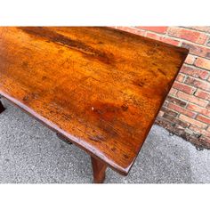 an old wooden table sitting in front of a brick wall