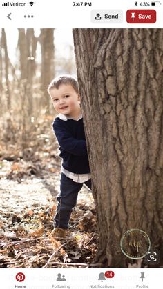 a little boy standing next to a tree in the woods with his arms wrapped around it