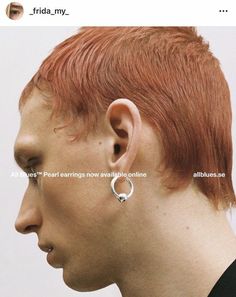 a man with red hair wearing silver hoop earrings