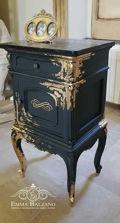 an antique black and gold painted cabinet with two clocks on it's top shelf