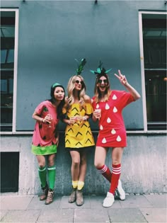 three women dressed up in costumes posing for the camera with one woman pointing to the side