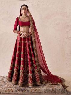 a woman in a red and gold lehenga is posing for the camera with her hands on her hips