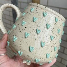 a hand holding a ceramic mug with hearts on it's side and the caption says, cultivation clay