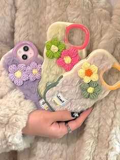 a person holding two cell phones with flowers on them and one has a pair of scissors