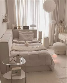 a white room with a bed, couch and table next to the window in it