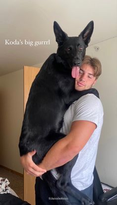 a man holding a large black dog in his arms