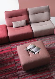 a living room with a couch, ottoman and book on the floor in front of it