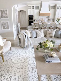 a living room filled with white furniture and lots of pillows on top of it's couches