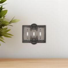 a wall mounted light switch plate with two lights on each side and an ornate design in the middle