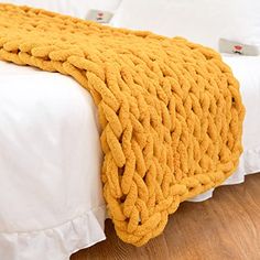 a yellow blanket sitting on top of a white bed