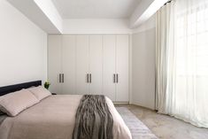 a bedroom with white walls and beige bedding