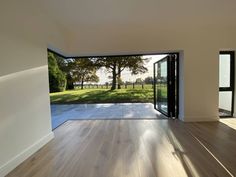 an empty room with wooden floors and sliding glass doors leading to a large open field