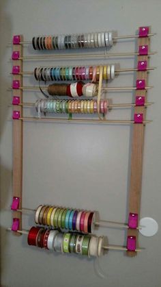 a wall mounted rack with many different colored spools on it and some tape