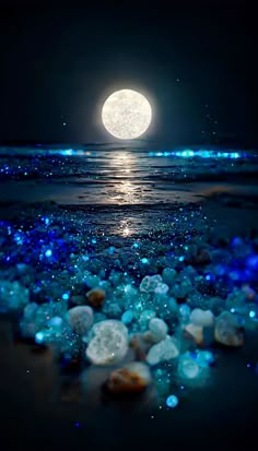 the full moon shines brightly in the night sky over water and rocks on the beach