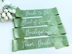 the bride and groom's names on green satin ribbons are next to a bouquet of flowers