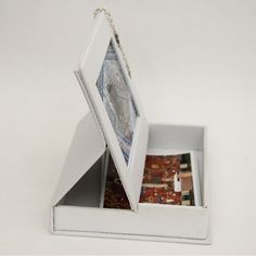 an open white box with pictures in it on a white surface, showing the contents inside