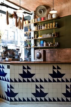 a kitchen with blue and white tiles on the wall, counter top and shelving