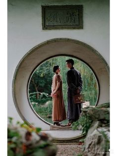 a man and woman standing in front of a circular window looking into each other's eyes