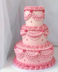 a three tiered cake with pink icing and ruffles