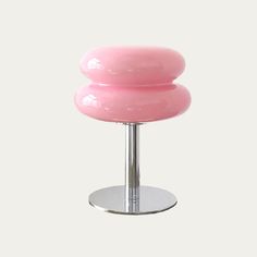 a pink stool sitting on top of a metal stand