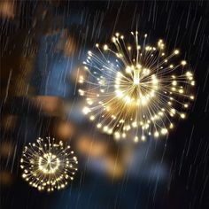 two fireworks are lit up in the dark with rain falling down on them and one is yellow