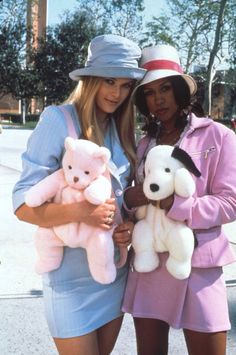 two women standing next to each other holding stuffed animals