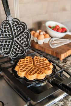 the waffles are being cooked on the stove with heart shaped waffle cutters