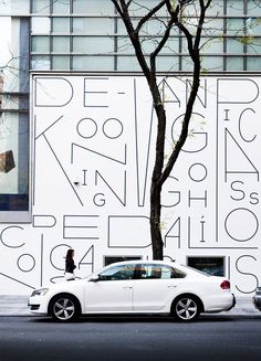 a white car parked in front of a building with graffiti on it's side