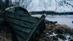 an old wooden boat sitting on the shore