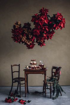 two chairs and a table with food on it in front of a wall decorated with red poinsettis