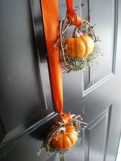 two pumpkins are hanging on the front door with hay and orange ribbon around them