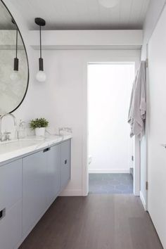 a bathroom with white walls and wood flooring next to a large mirror on the wall