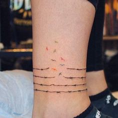 a woman's ankle with barbed wire and birds on the top of her leg