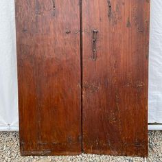 two old wooden doors sitting next to each other on top of a stone floor covered ground