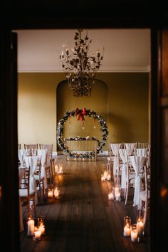 a room filled with lots of chairs covered in white table cloths and lit candles