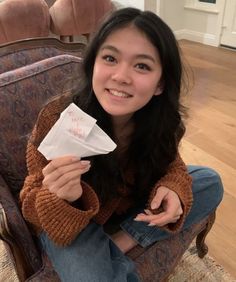 a woman sitting on a chair holding a piece of paper