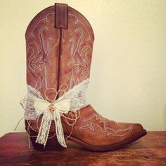 a pair of brown cowboy boots with white lace tied around the toe and heel, sitting on a wooden table