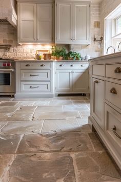 a kitchen with white cabinets and stone flooring is shown in this image from the front view