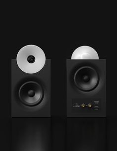 two speakers are shown side by side in black and white colors on a dark background