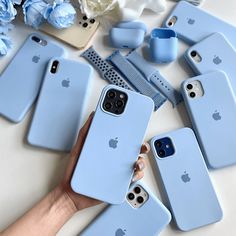 several blue iphone cases sitting on top of a white table next to flowers and combs