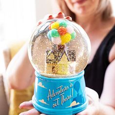 a woman holding a snow globe with gummy balls in it's center and the words adventure is not there