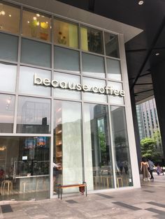 the entrance to a coffee shop with people walking in front and sitting at tables outside