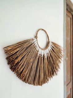 a wall hanging made out of straw with a circle shaped decoration on the side of it