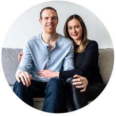 a man and woman sitting on top of a couch next to each other in front of a white circle