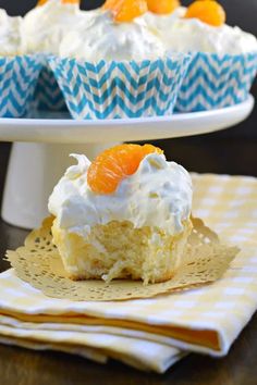 two cupcakes with frosting and oranges on top are sitting on plates