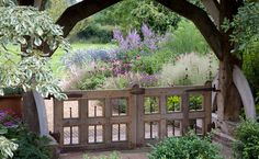 a wooden gate surrounded by plants and flowers