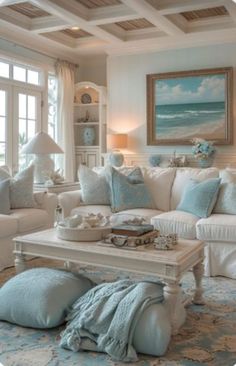 a living room filled with white furniture and blue pillows on top of it's couches